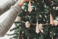 17 a woodland Christmas tree with pompom garlands, lights, wooden tree-shaped ornaments and burlap ribbons is a creative and cool idea