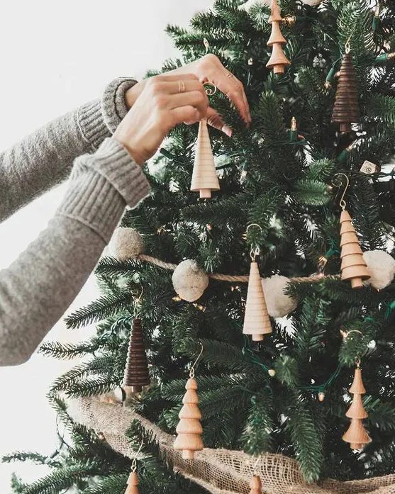 a woodland Christmas tree with pompom garlands, lights, wooden tree-shaped ornaments and burlap ribbons is a creative and cool idea