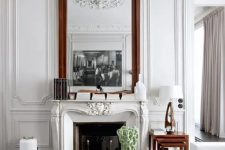 18 a carved vintage white fireplace with a metal stand and a glass screen for a cozy feel adds chic and interest to this refined living room