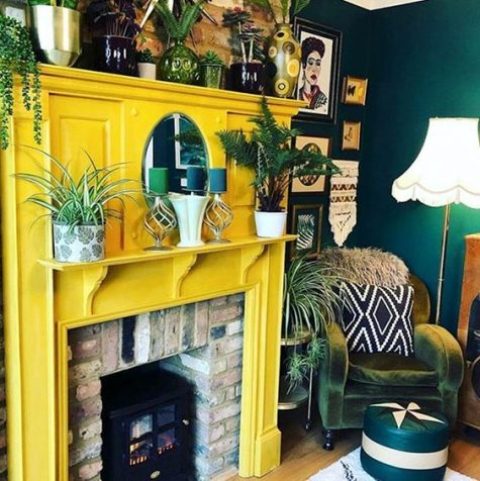 a brick fireplace with a sunny yellow surround, lots of plants and candles is a very cozy idea that will add a bit of sun here