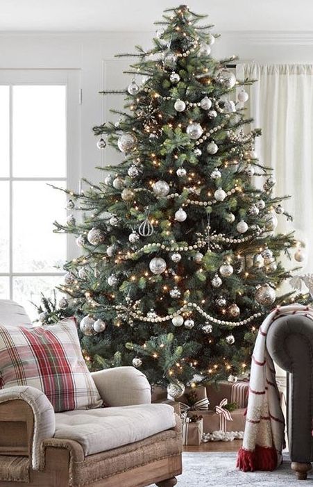 a large neutral Christmas tree with silver and gold ornaments, lights and shiny bead garlands plus rhinestone snowflakes is wow