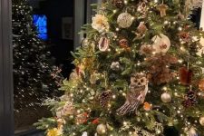 19 an oversized woodland glam Christmas tree with gold and green ornaments, pinecones, owls, vines, lights and branches plus some faux blooms