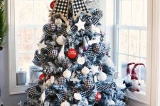 20 a farmhouse Christmas tree with buffalo check ribbons, red and white printed ornaments, a buffalo check bow and a snowflake on top