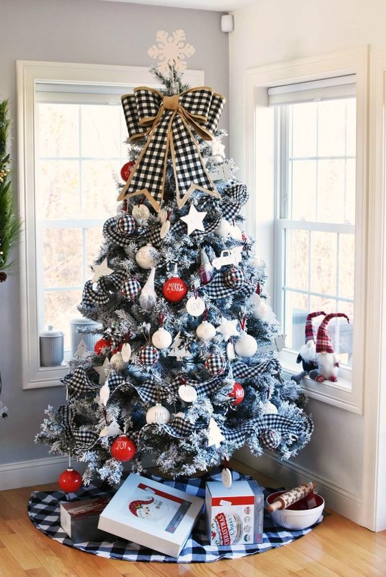 a farmhouse Christmas tree with buffalo check ribbons, red and white printed ornaments, a buffalo check bow and a snowflake on top