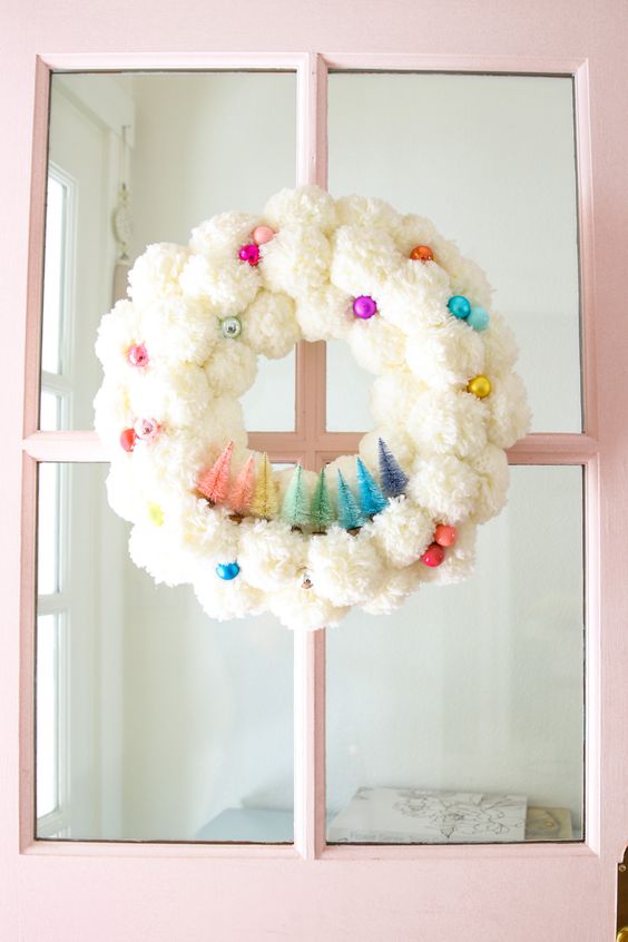 a fluffy white pompom Christmas wreath with colorful ornaments and matching bottle brush trees is a fun touch to your space