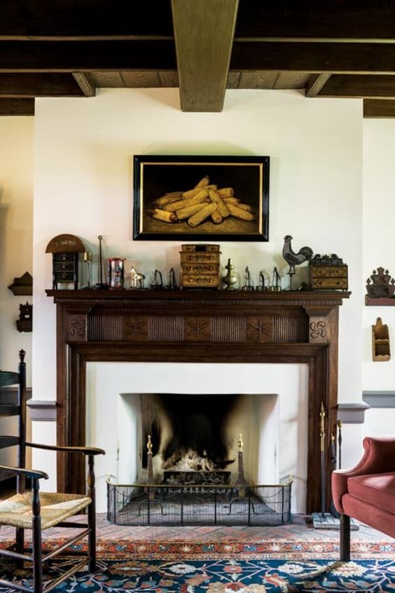 a gorgeous vintage fireplace with a jaw dropping vintage stained ornated wooden mantel, with stylish decor and a bold artwork
