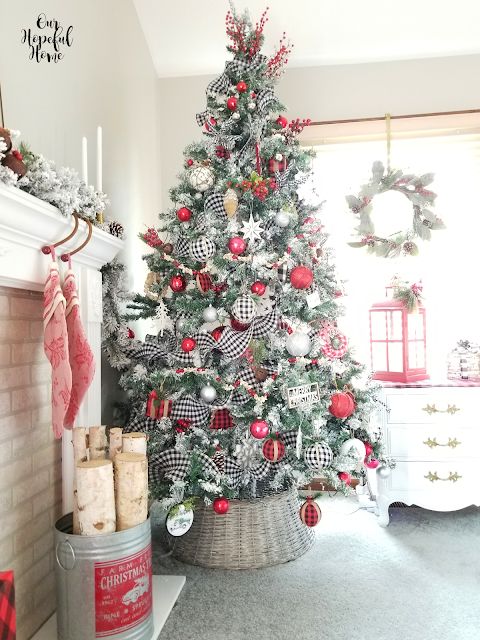 a lovely flocked Christmas tree with red, silver, buffalo check ornaments, stars, snowflakes and berry branches on top