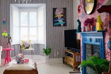 21 a maximalist living room with a striped wall, a bold floral one, a bright blue mantel over a vintage fireplace, a crystal chandelier and touches of hot pink