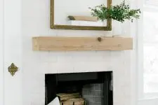 21 a stylish whitewashed brick fireplace with a wooden mantel, a mirror and greenery plus printed pillows for a cozy feel