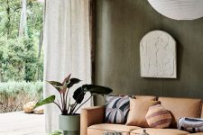 22 a beautiful sustainable living room with textural green walls, wooden furniture, potted plants, a leather sofa and textural rugs