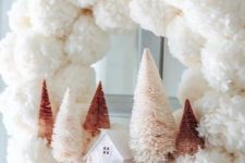 22 a delicate white pompom Christmas wreath with blush and rustic bottle brush trees and a mini house plus a mauve bow