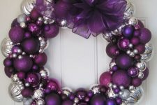 22 a gorgeous Christmas wreath of purple, silver ornaments of various sizes and an oversized bow on top is a bold decoration