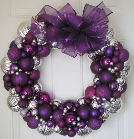 a gorgeous Christmas wreath of purple, silver ornaments of various sizes and an oversized bow on top is a bold decoration