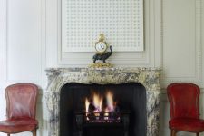 22 a large black vintage fireplace with a fantastic stone vintage mantel, red leather chairs to accent it