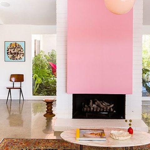 a modern white brick fireplace with a bright plain pink accent over it is a beautiful color feature in this mid century modern space