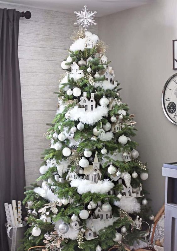 a whimsical neutral Christmas tree with white and silver ornaments, white faux fur garlands, berries, branches, houses and a snowflake tree topper