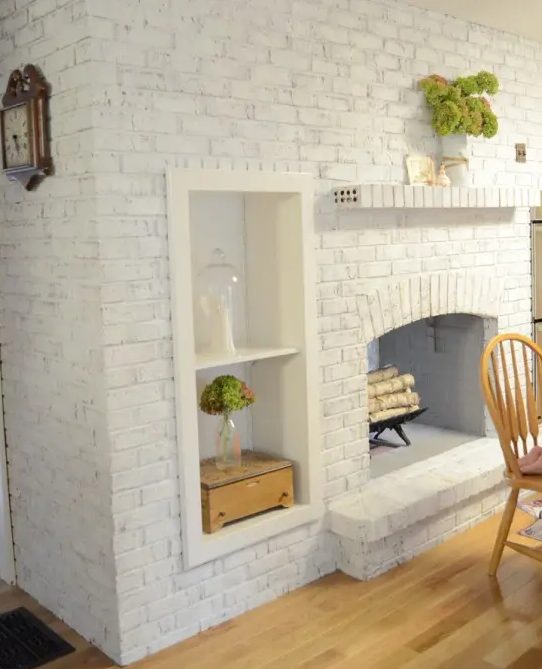 an oversized whitewashed brick non working fireplace with built in shelves and potted greenery is a stylish and cozy decoration