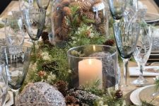 23 a chic forest Christmas tablescape with evergreens, small and large pinecones, candles, smoked glasses and a shiny twine ball