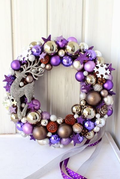 a pretty bright Christmas wreath with lilac, purple, silver and gold ornaments, tiny pinecones and a rhinestone deer is a lovely and bold front door decoration