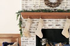 24 a chic whitewashed brick fireplace with a wooden stained mantel, baskets, candle lanterns and stockings for Christmas