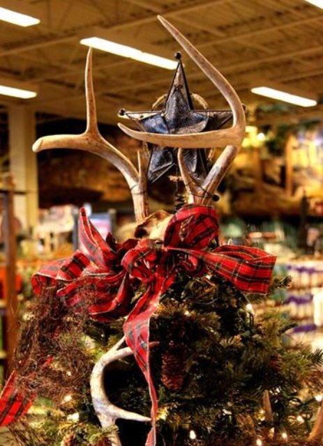 a leather star paired with antlers and a red plaid ribbon bow is a fantastic Christmas tree topper for a woodland-inspired space