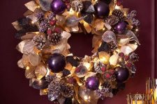 24 a refined Christmas wreath of gilded and dark leaves, purple ornaments, pinecones, lights and faux berries is fantastic idea
