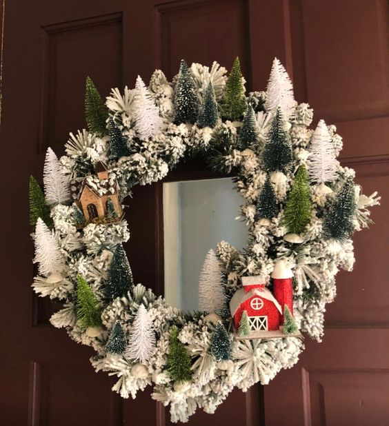 a lovely snowy Christmas wreath with white and green bottle brush Christmas trees and some houses is cute