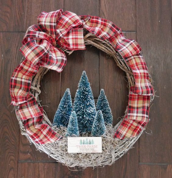 a vine and plaid ribbon Christmas wreath with green bottle brush trees and a tree farm sign is a cozy idea