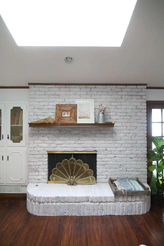 a large whitewashed brick fireplace with its lower part extended as a bench, a small mantel and a beautiful gold screen