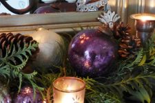 28 delicate and refined Christmas mantel decor with greenery, pinecones, purple and silver ornaments and candleholders is very chic and cool
