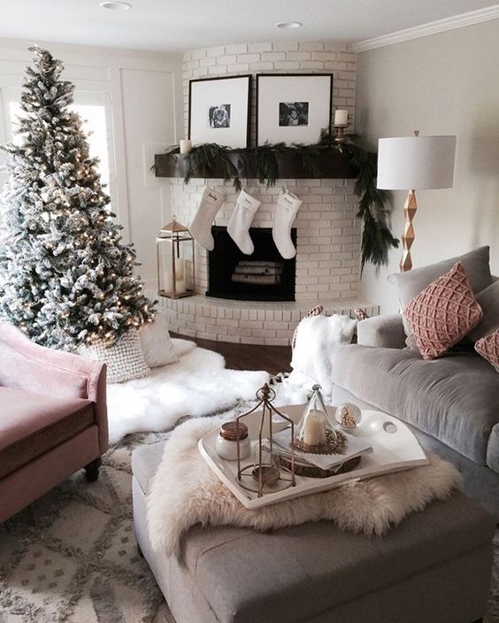 a Christmas living room with a whitewashed brick fireplace and a mantel dressed up with evergreens, a gorgeous tree and faux fur