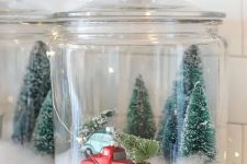 29 a Christmas terrarium made of a large jar with faux snow, bottle brush trees and a large truck plus lights around