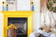 29 a sunny yellow fireplace, a bold blue ottoman and blue bottles with sunflowers to make the space bolder