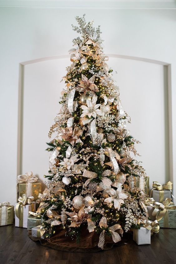 a super glam and shiny Christmas tree decorated with rose gold, silver and gold ornaments, fabric blooms and lights plus faux silver berries on top