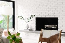 31 a mid-century modern fireplace clad with whitewashed brick, with a stone bench under it instead of a mantel, stylish modern furniture
