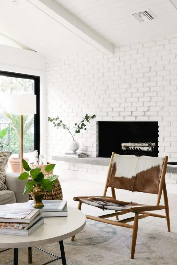 a mid-century modern fireplace clad with whitewashed brick, with a stone bench under it instead of a mantel, stylish modern furniture