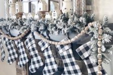 31 buffalo check stockings, flocked evergreens and wooden bead garlands for Christmas mantel decor