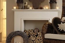31 elegant woodland Christmas decor with a deer head silhouette, mini potted trees, candles and pillar candles, firewood in the fireplace and a simple vine wreath