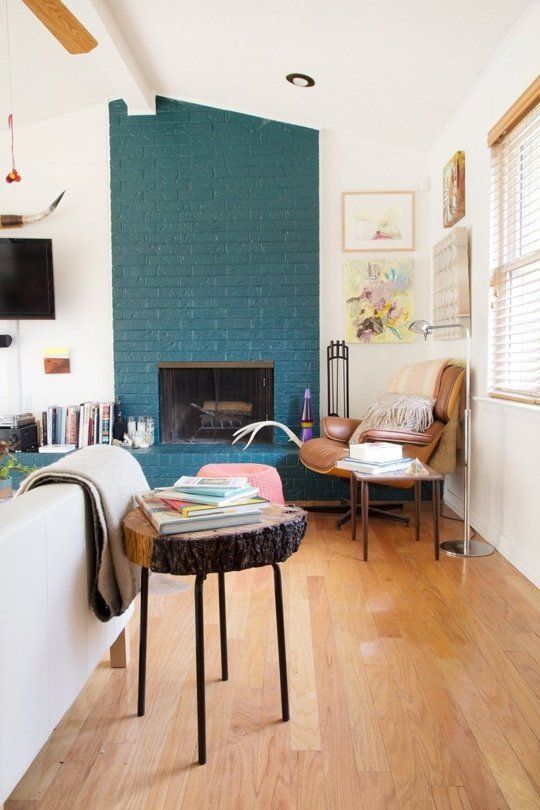 a cool mid-century modern living room with a teal painted brick fireplace and chic modern furniture is amazing