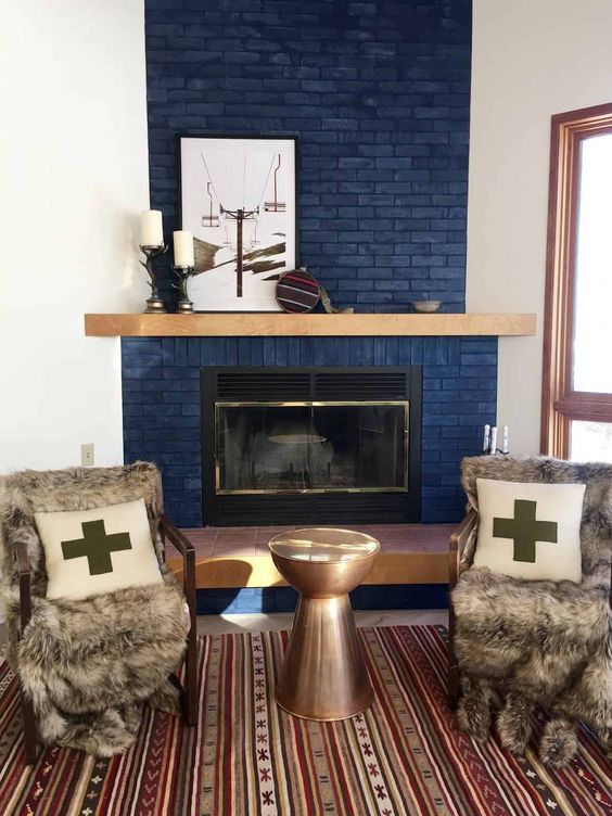 a modern space wiht a navy brick fireplace, a boho rug, a metal sid etable and upholstered chairs with faux fur