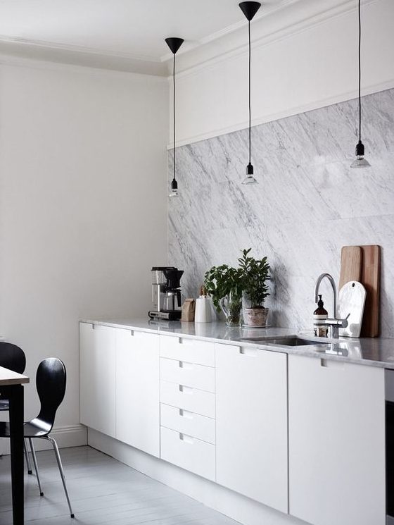 a modern white kitchen with a white marble tile backsplash and countertops looks chic, elegant and stylish