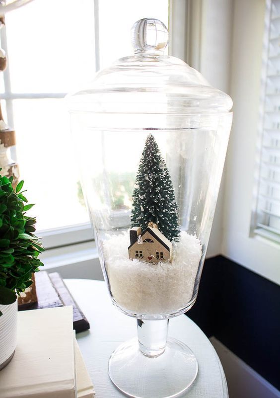 a pretty Christmas snow globe with faux snow, a cardboard house and a bottle brush tree is a lovely idea