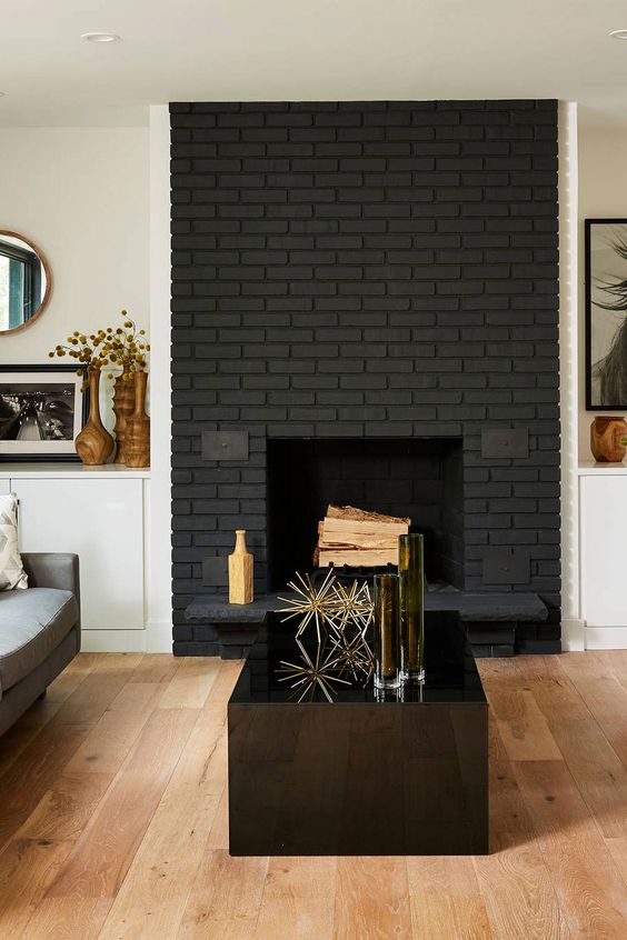 a chic modern space with a black brick fireplace, elegant furniture, a glossy black coffee table with gold decor