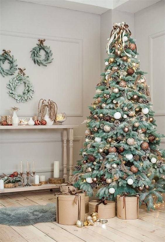a refined Christmas tree with white, gold, silver and brown ornaments, pinecones, vines and white and brown ribbons on top