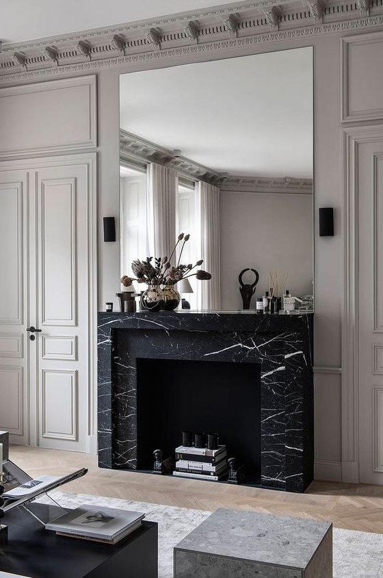 a refined living room with a large non-working fireplace clad with black marble for a chic touch