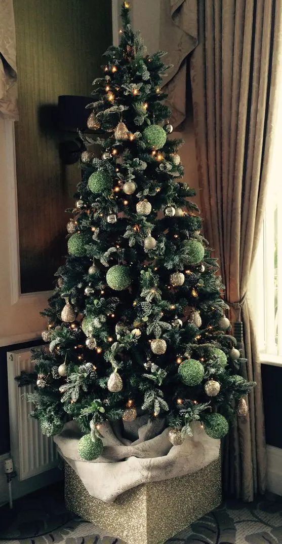 a Christmas tree decorated with green and gold glitter ornaments and lights is a super chic and glam idea