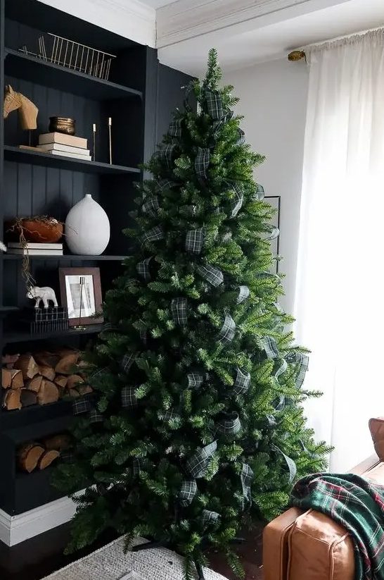 a Christmas tree decorated with only dark green plaid ribbon and nothing else is a very fresh and bold solution with a rustic feel