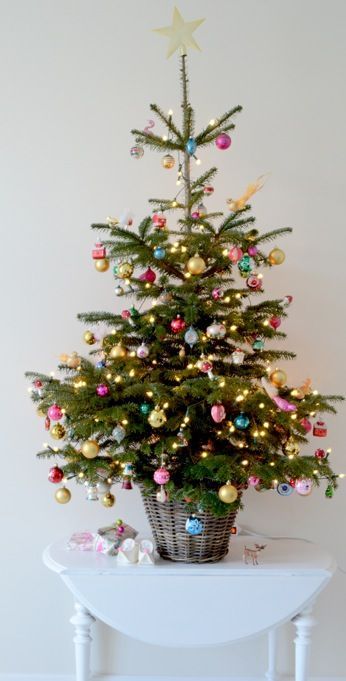 a Christmas tree in a basket, colorful vintage ornaments, lights and a gold star tree topper is a cool and bright idea