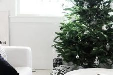 a Christmas tree with black, white and clear glass ornaments is a pretty idea for a modern space and it looks amazing