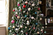 a Christmas tree with colorful vintage ornaments and beaded garlands plus lights for a chic and bold look